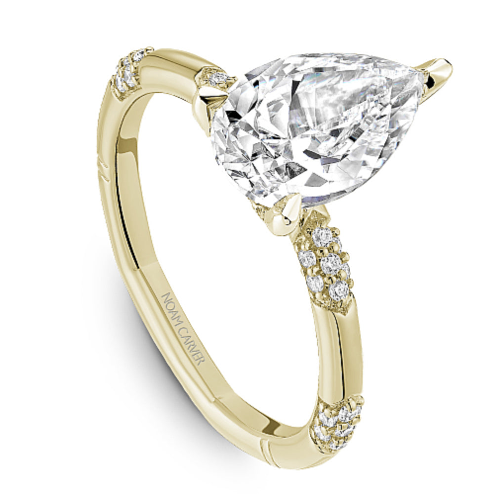 Gold Noam Carver ring with a pear-shaped diamond and pave diamond station sides on a white background