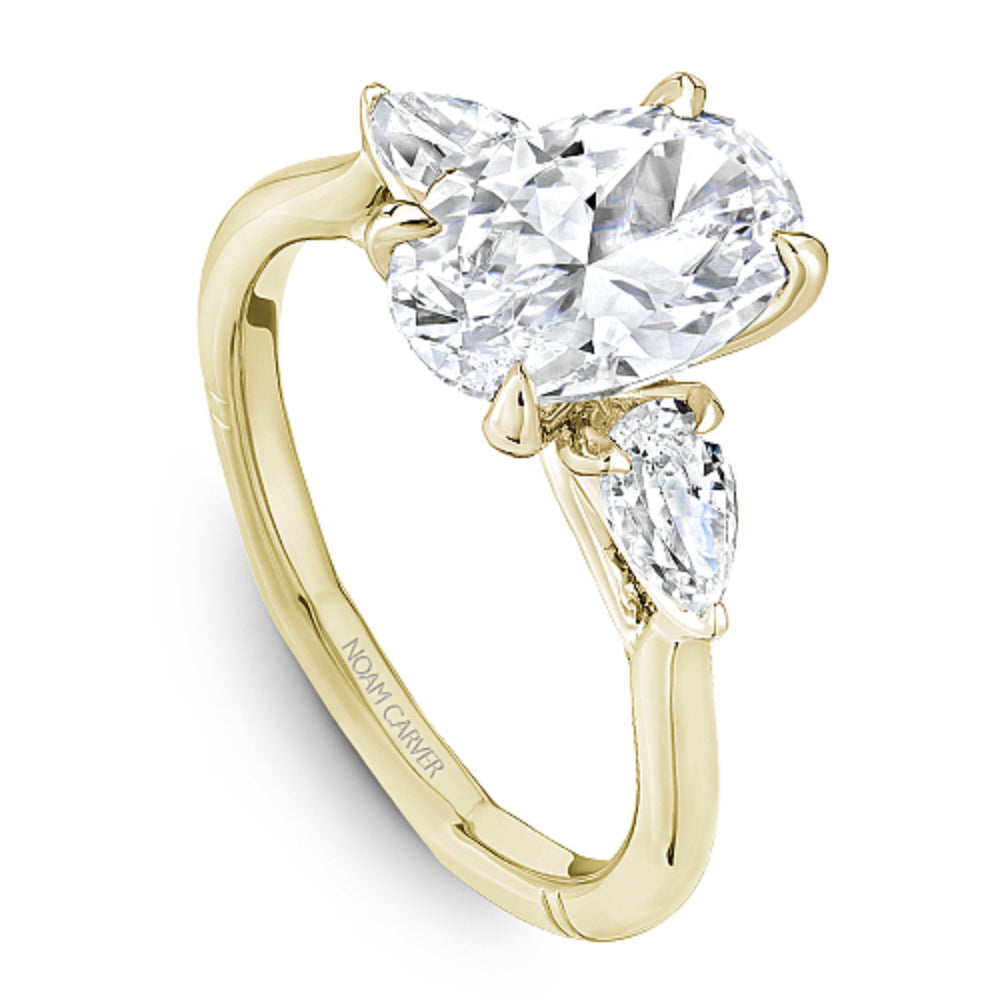 Gold Noam Carver ring with a large oval diamond center and two pear shape diamond sides on a white background