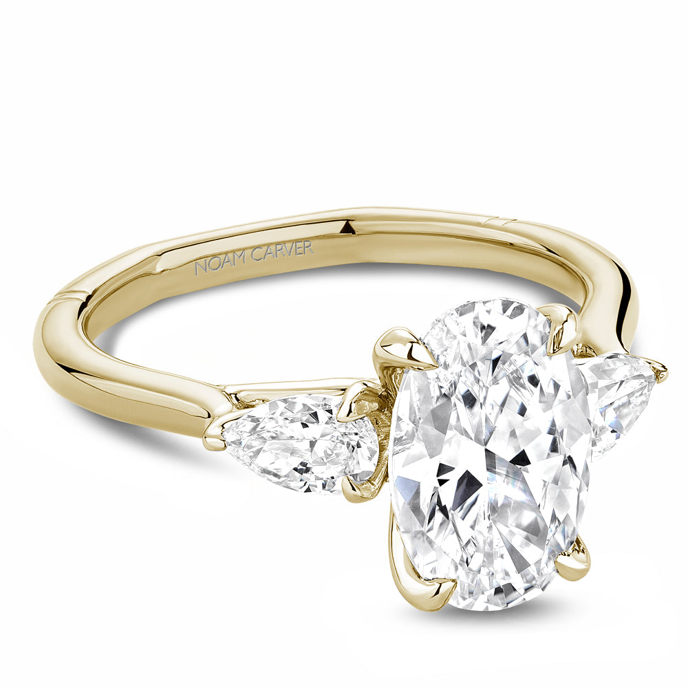 Gold Noam Carver ring with a large oval diamond center and two pear shape diamond sides on a white background