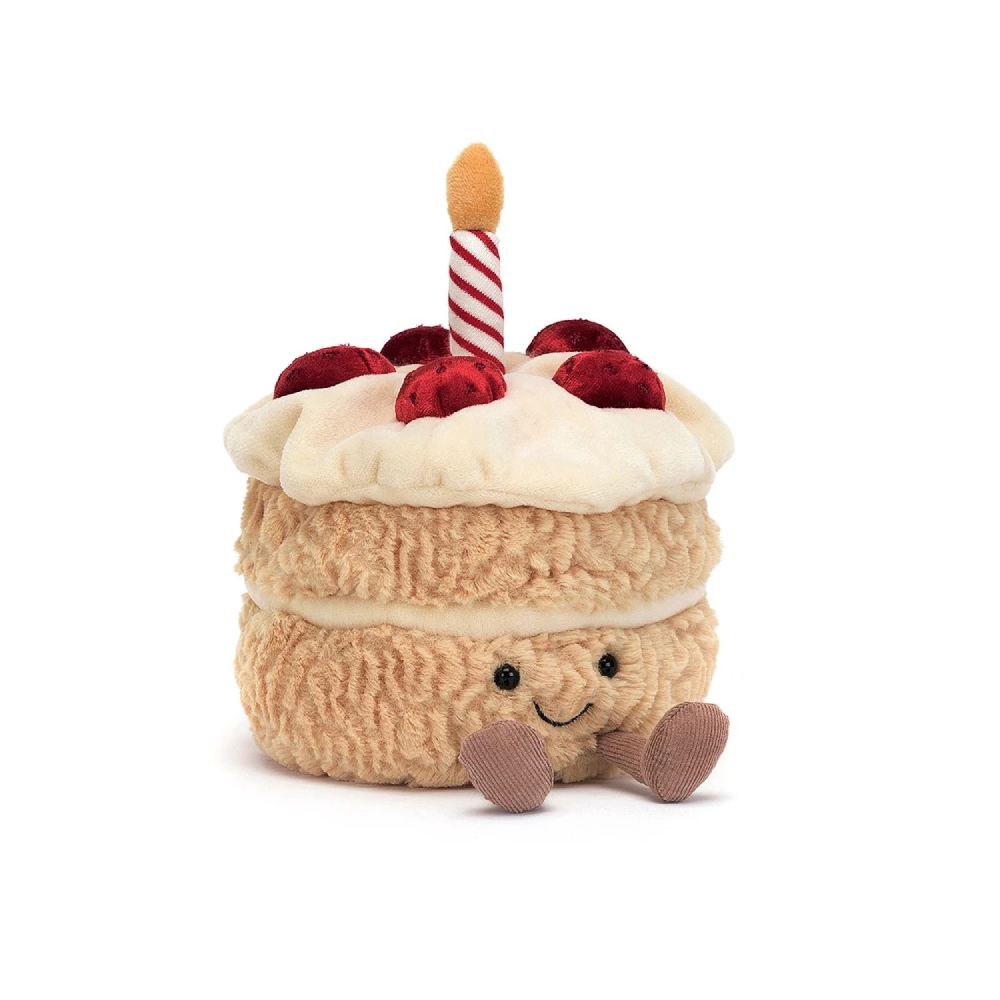 A plush toy resembling a birthday cake with two layers, decorated with a red and white striped candle on top, and sliced pieces on the side.