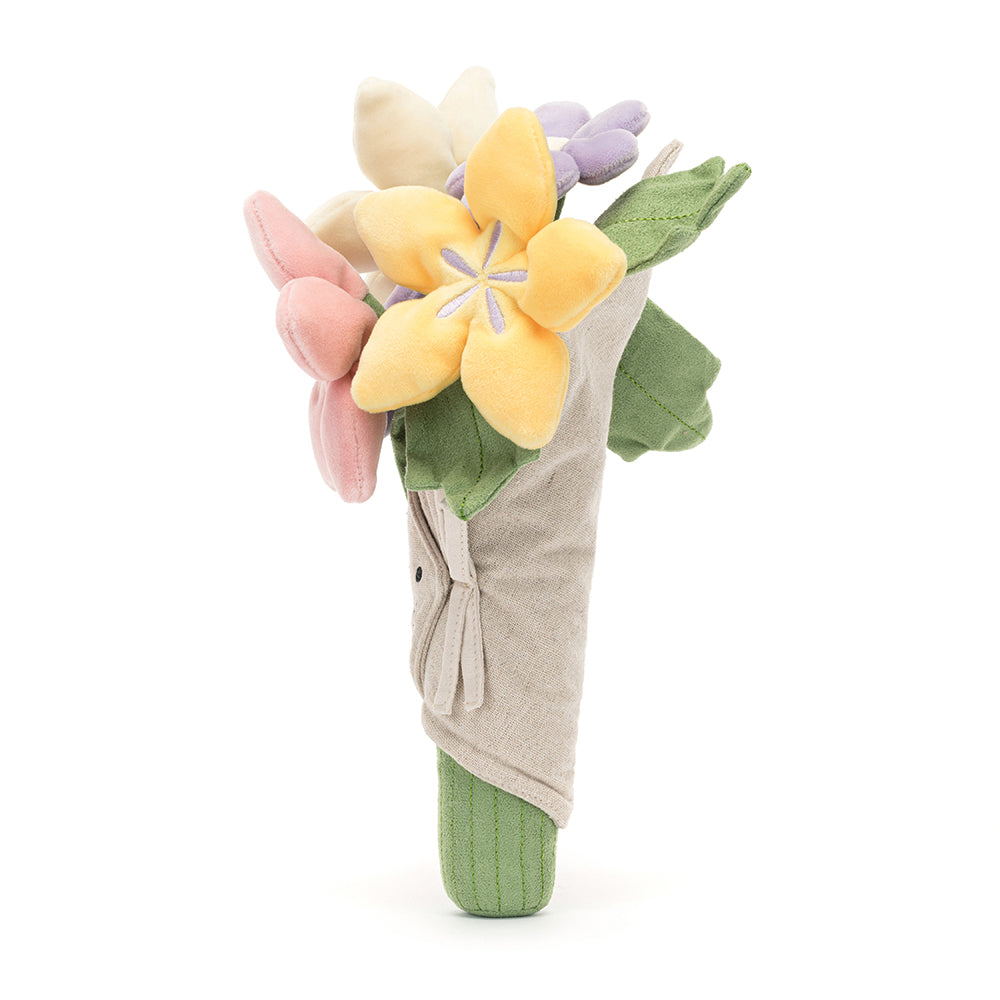 A plush toy bouquet of flowers with a variety of colors including pink, purple, and yellow, with a smiling face at the center, wrapped in beige fabric. Side of item.