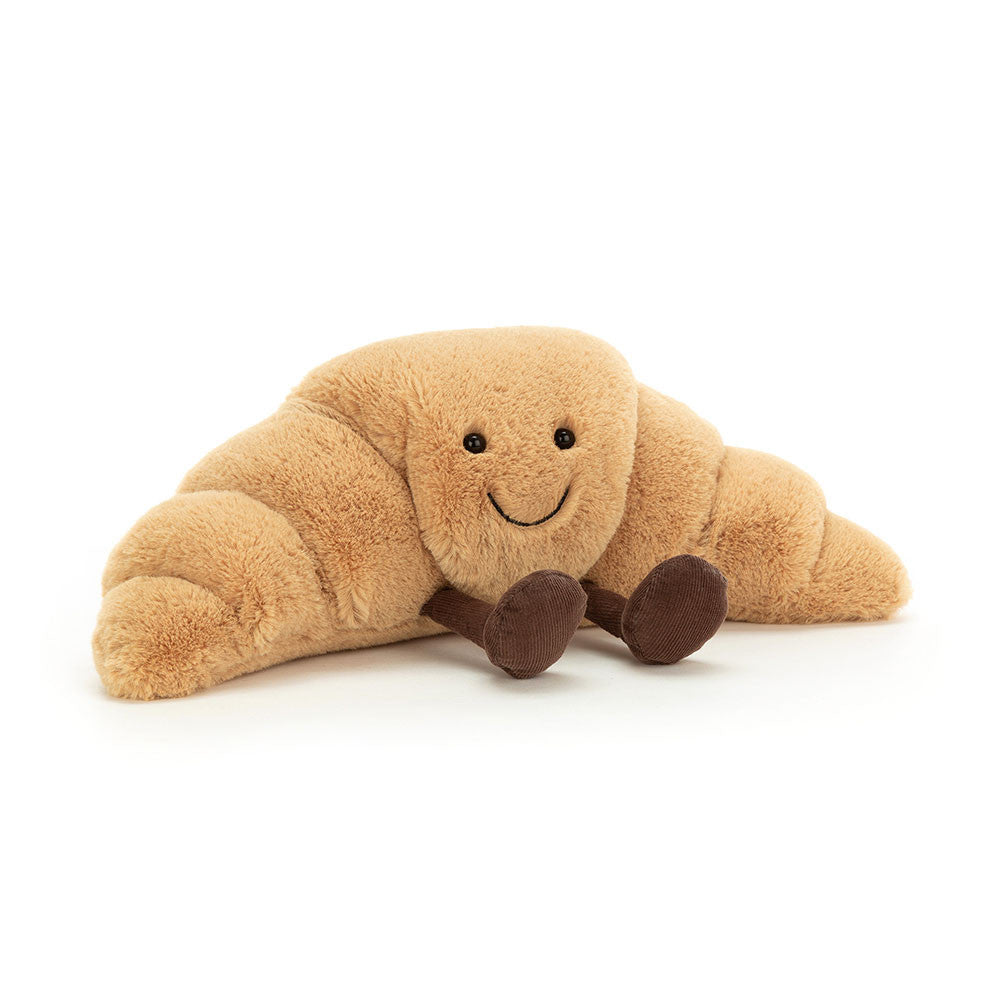 A medium sized plush toy resembling a croissant with a happy facial expression and chocolate colored boots on a white backround.