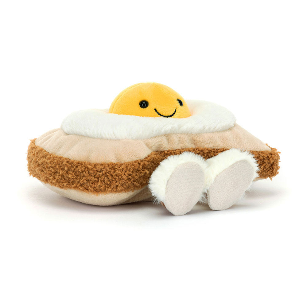 A angled side photo of a plush toy resembling a egg on toast with a smiley face on a white background