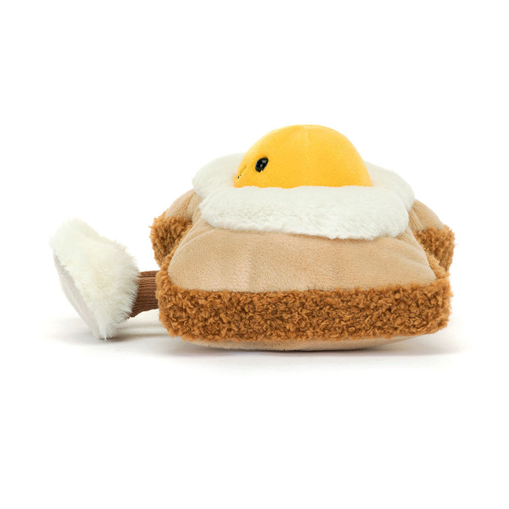 A side photo of a plush toy resembling a egg on toast with a smiley face on a white background
