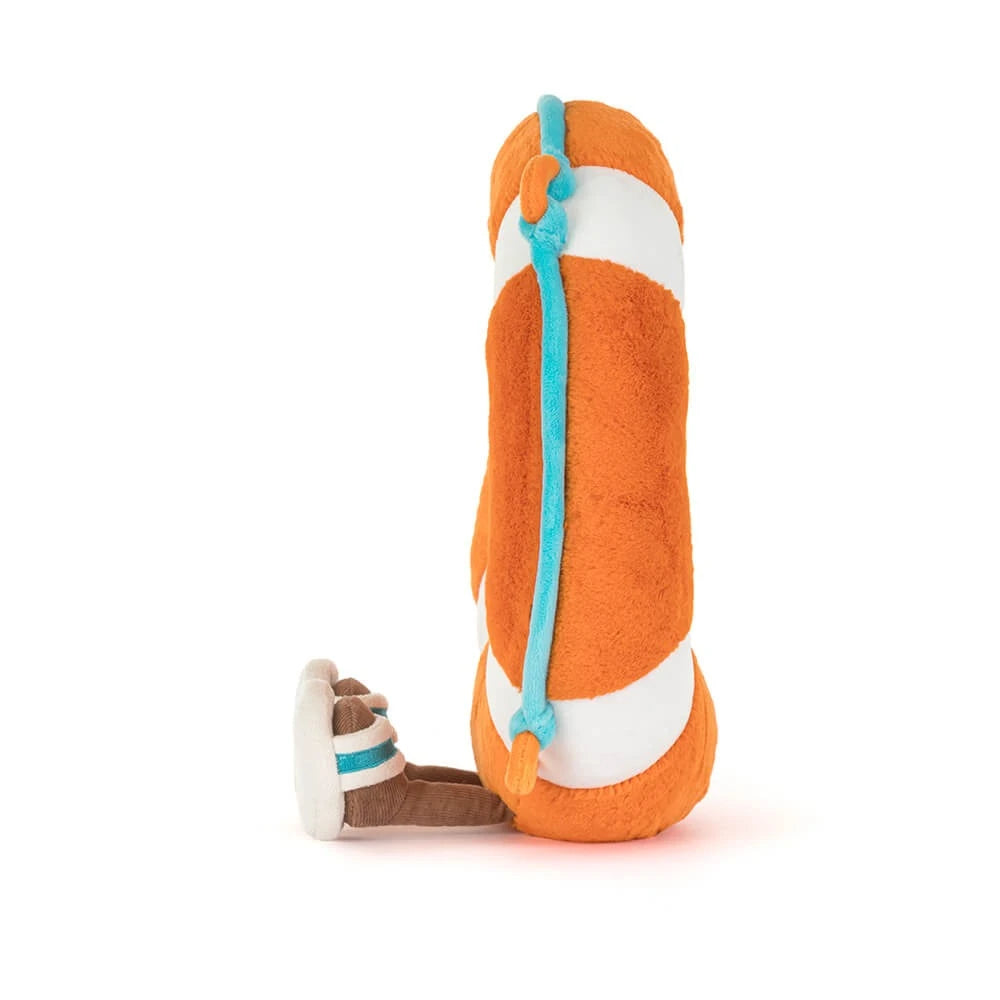 A side photo of a plush toy of a orange  & white striped life ring that says "Jellycat" in white letters with a face and brown legs with white sandles on a white backround.