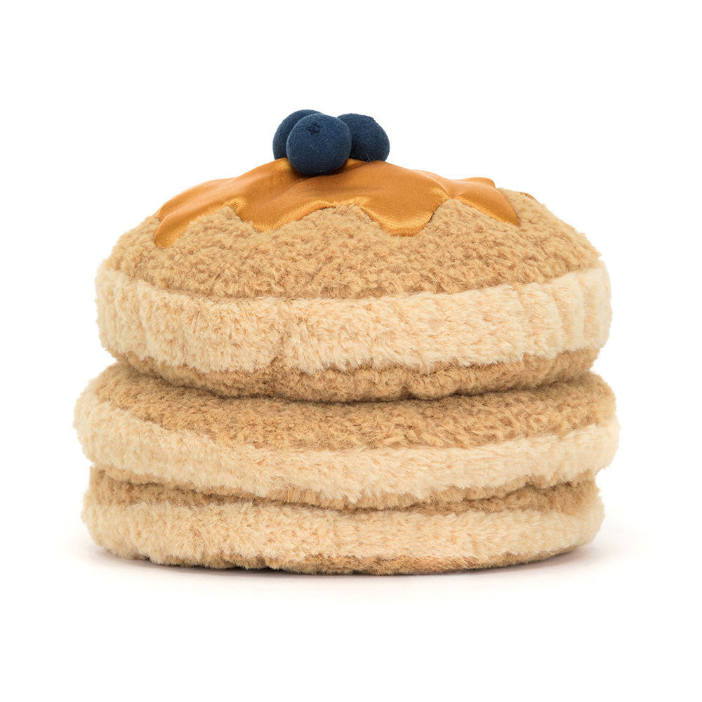 The back of a plush toy resembling a stack of pancakes with syrup and blueberries on top, with a smiling face and corduroy legs.