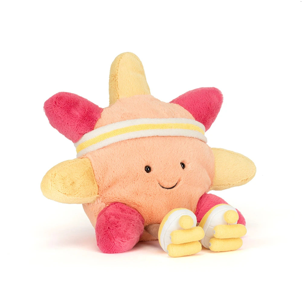 An angled side photo of a sun themed plush toy, with roller skates in orange, pink and  yellow, with a white and yellow headband with yellow and white skates and brown legs on a white background