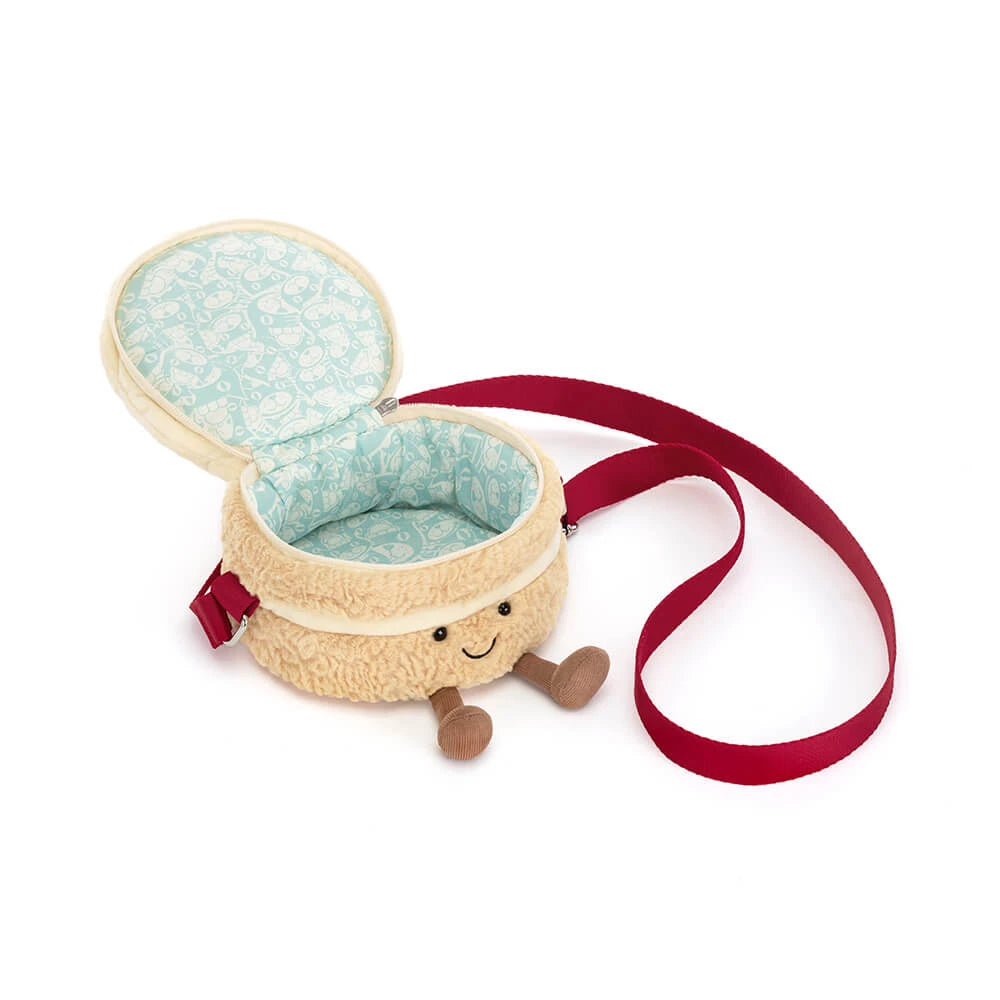 A plush baby carrier bag shaped like a smiling hot air balloon, featuring a cream-colored textured exterior, a light blue patterned fabric lining, and a red shoulder strap, shown on a white background.