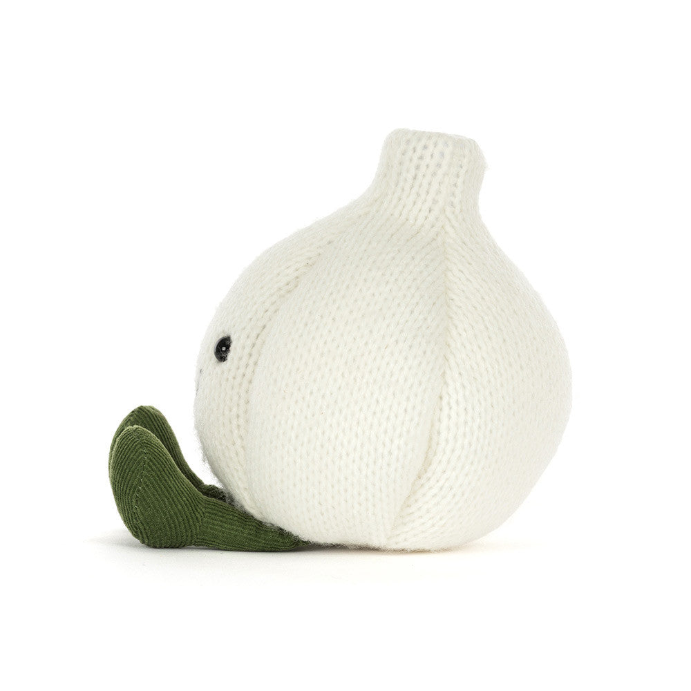 The side of a knitted garlic character plush toy with a smiling face and olive green feet, photographed against a seamless white background.