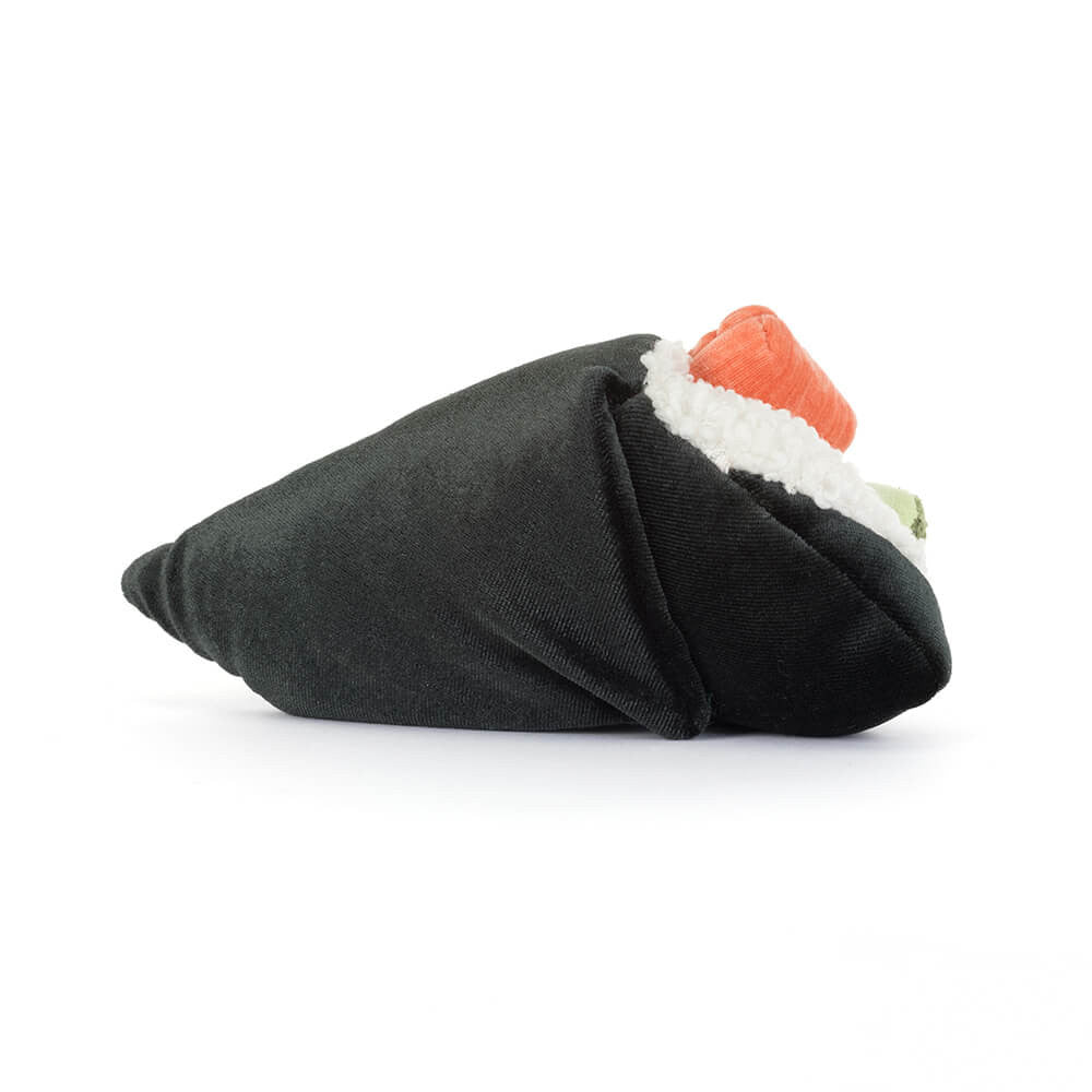 A photo of the back of a plush toy resembling a sushi roll with rice, pink salmon, and green wasabi with a smiling face and brown legs on a white background.