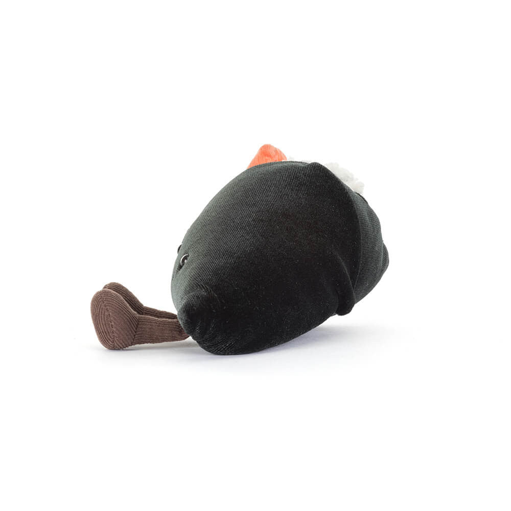 A photo of the side of a plush toy resembling a sushi roll with rice, pink salmon, and green wasabi with a smiling face and brown legs on a white background.