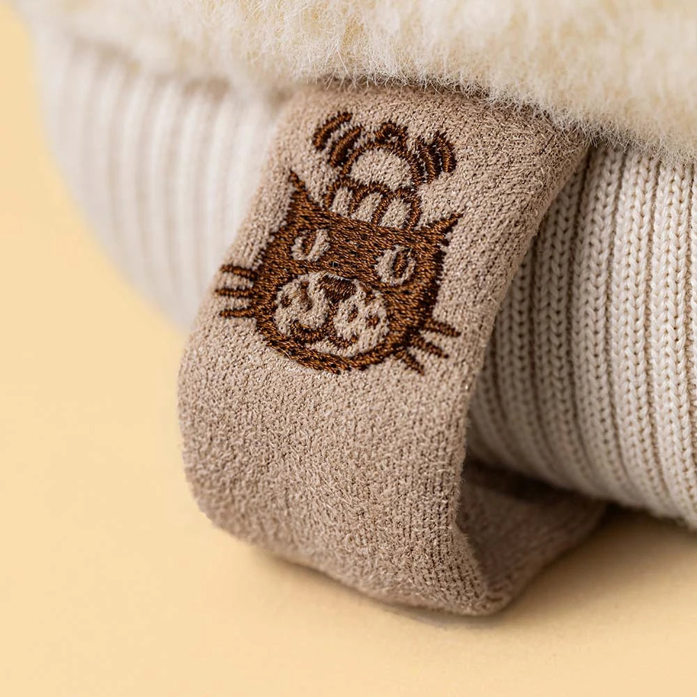 A close up of a Jellycat Mitten plush toy on a beige background. 