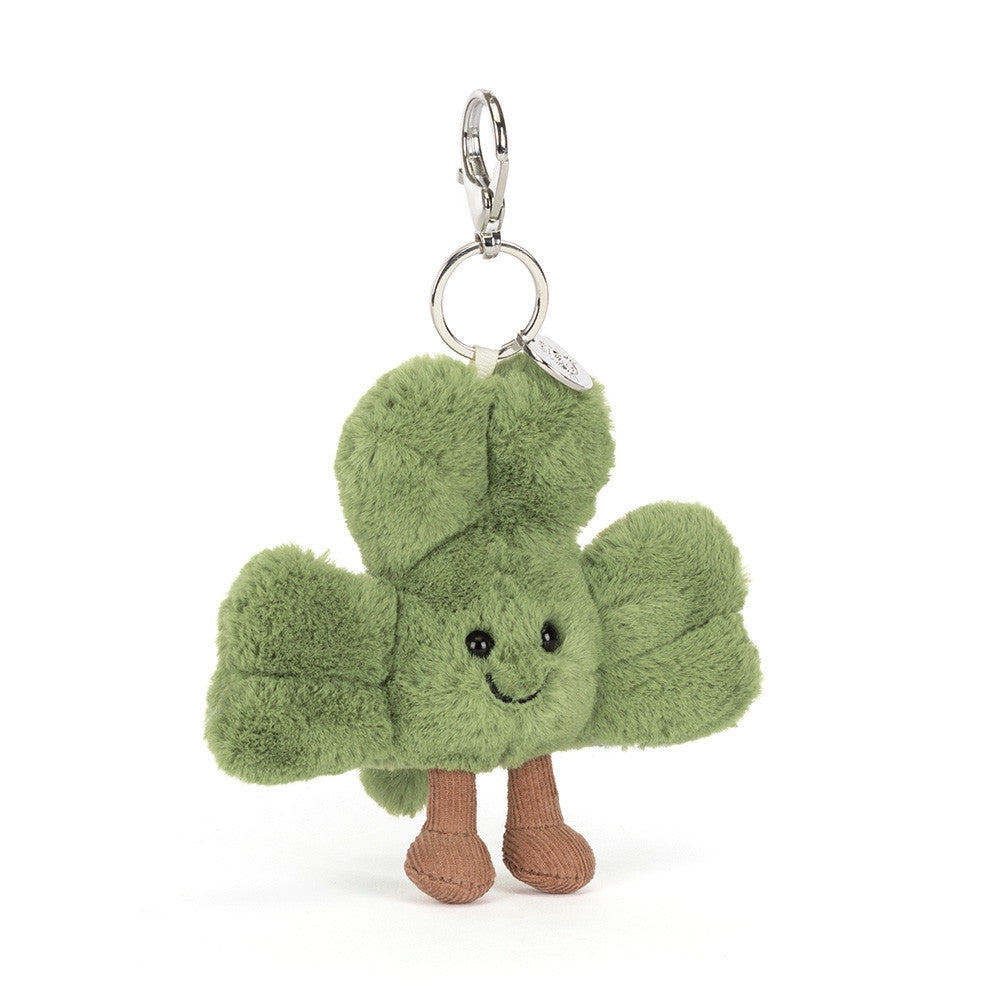 An angled facing photo of a Plush green shamrock keychain with a smiling face on a white background