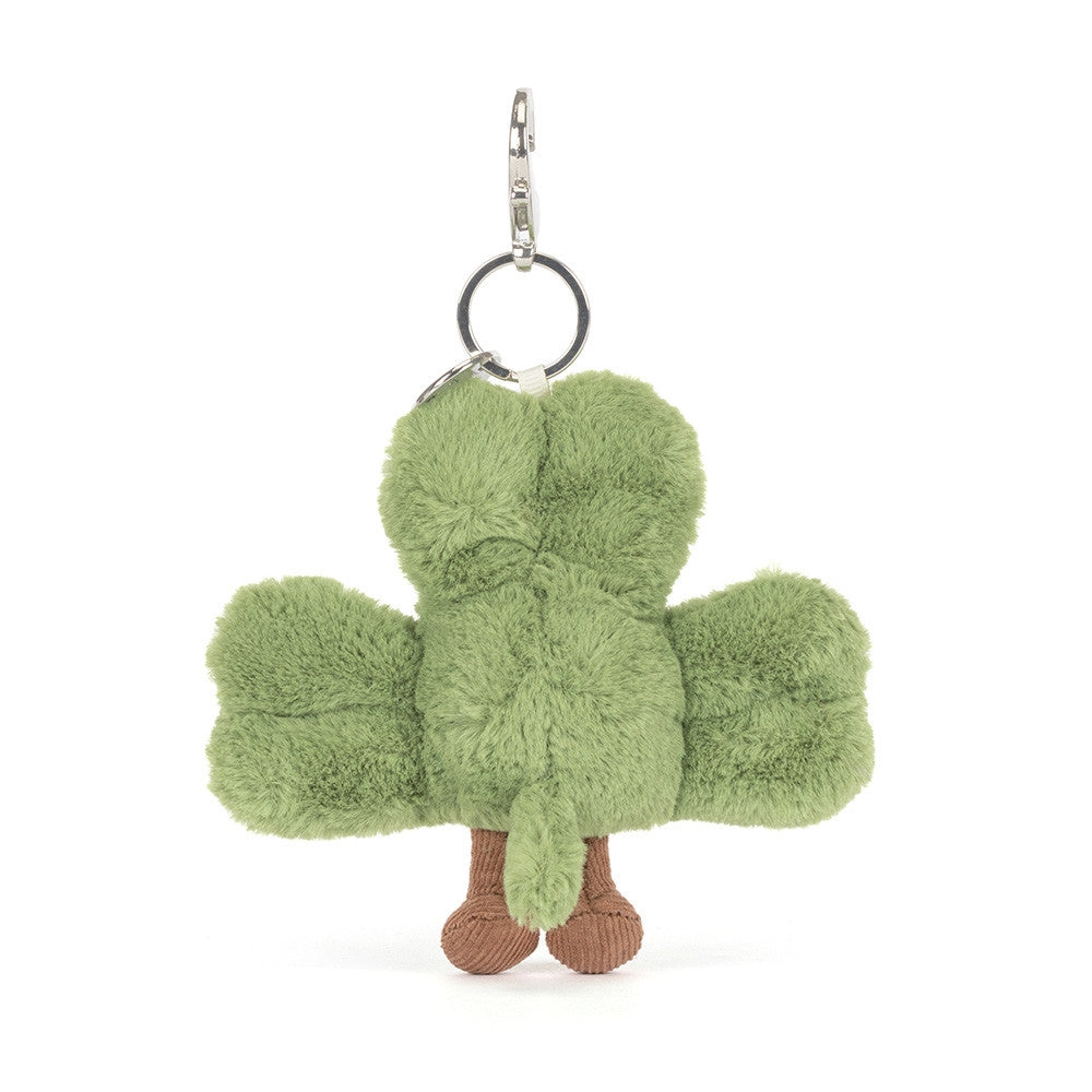 A back side facing photo of a plush green  shamrock keychain with a smiling face on a white background