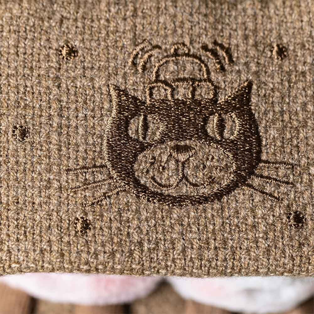 a close up of a embroidered Jellycat logo design on a textured brown surface.