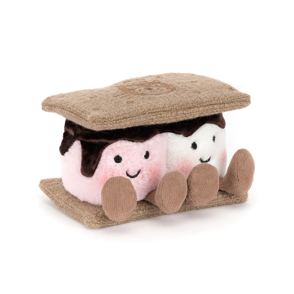 A side angled photo of a plush toy resembling a s'more with brown gram cracker with pink and white marshmallows and chocolate on a white background.