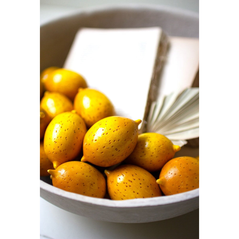 White bowl filled with yellow fruits on a white background