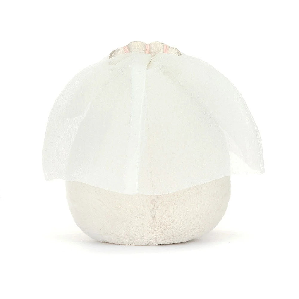 A  photo of the back of  a plush toy representing a boiled egg dressed as a bride, with a white veil and a yellow face, sitting upright with cocoa cordy legs.