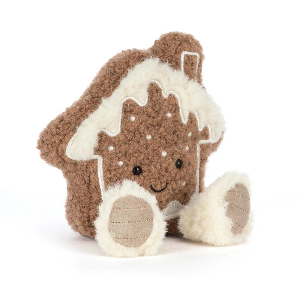 A plush gingerbread house plush toy with a brown curly-textured body, cream-colored icing details, embroidered facial features, and two small plush feet, photographed on a clean white background.