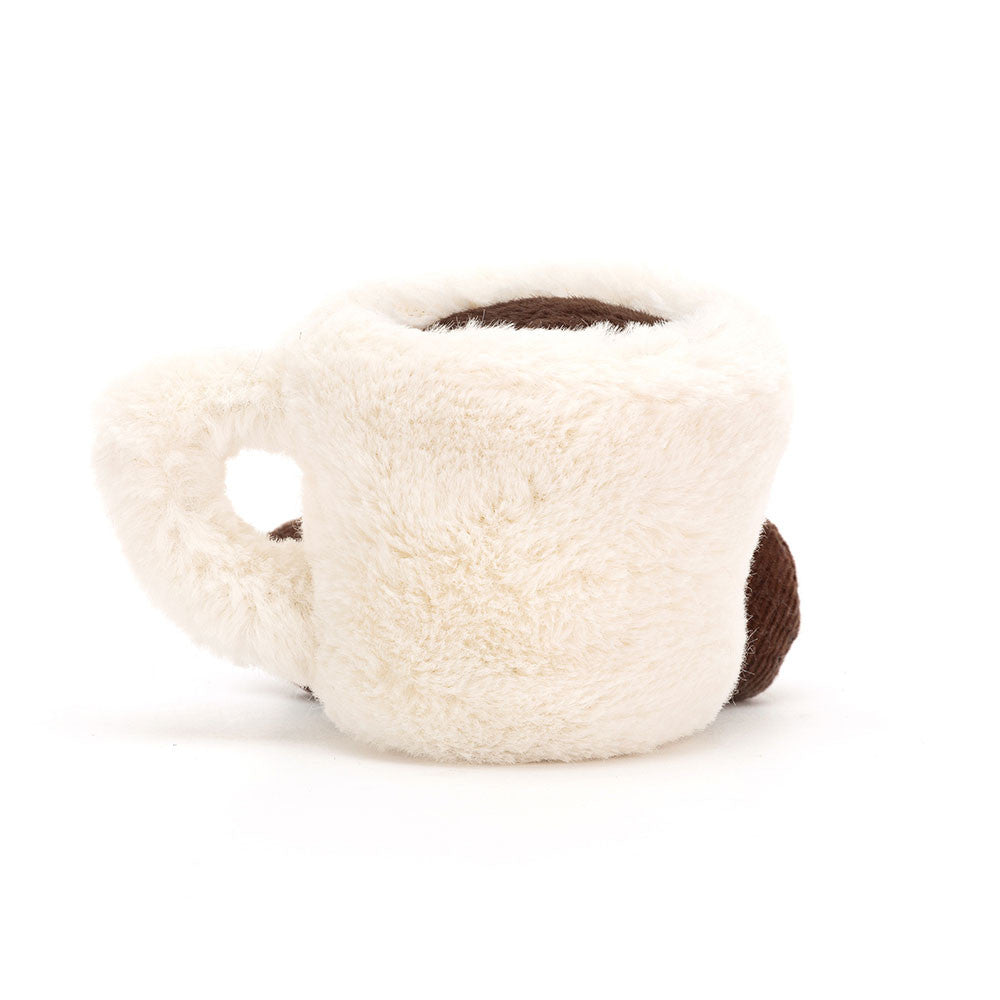 A  photo of the back of a stuffed white Espresso Cup toy with a smiling face and brown legs on a white background.