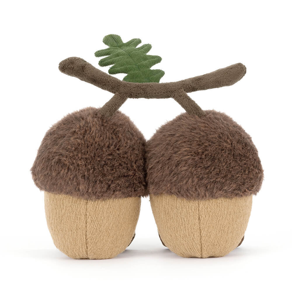 A photo of the back of a stuffed toy acorn with a branch on a white background.