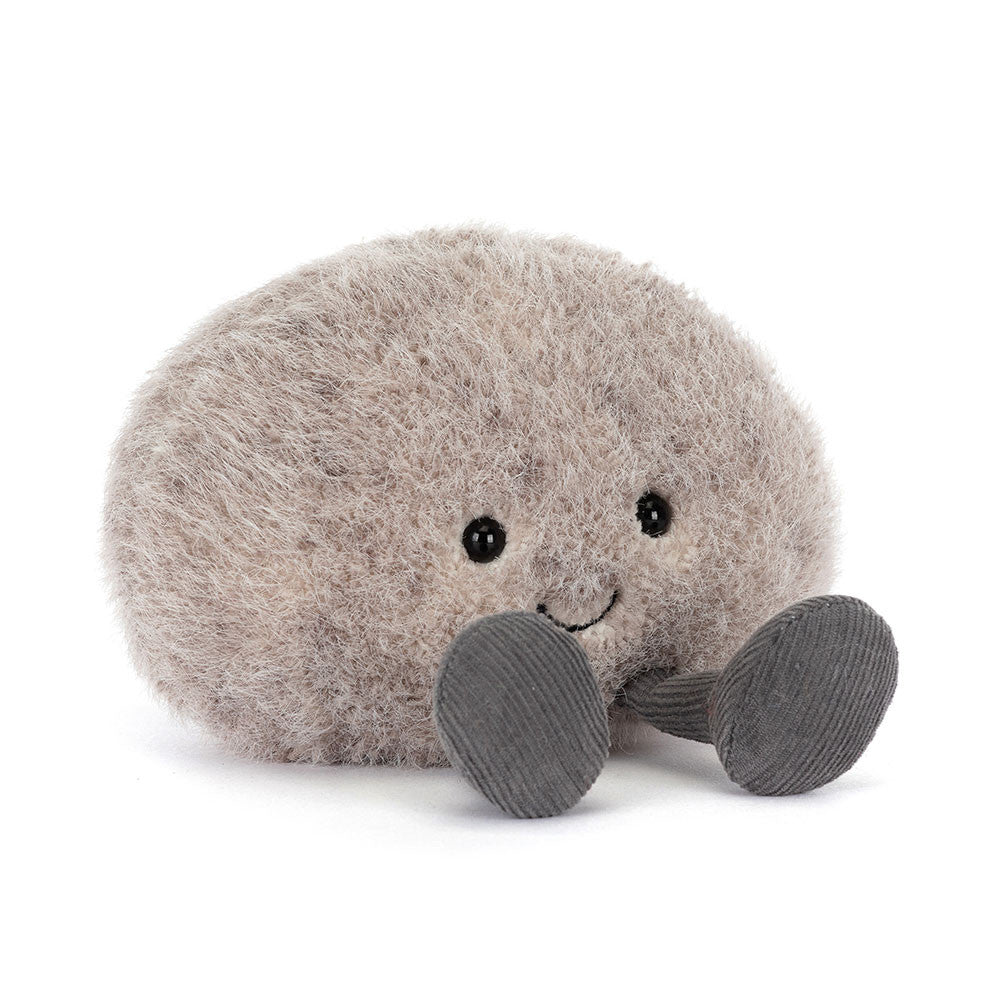 A angled side photo of an grey plush toy resembling a pebble with a smiling face and grey legs on a white backround.