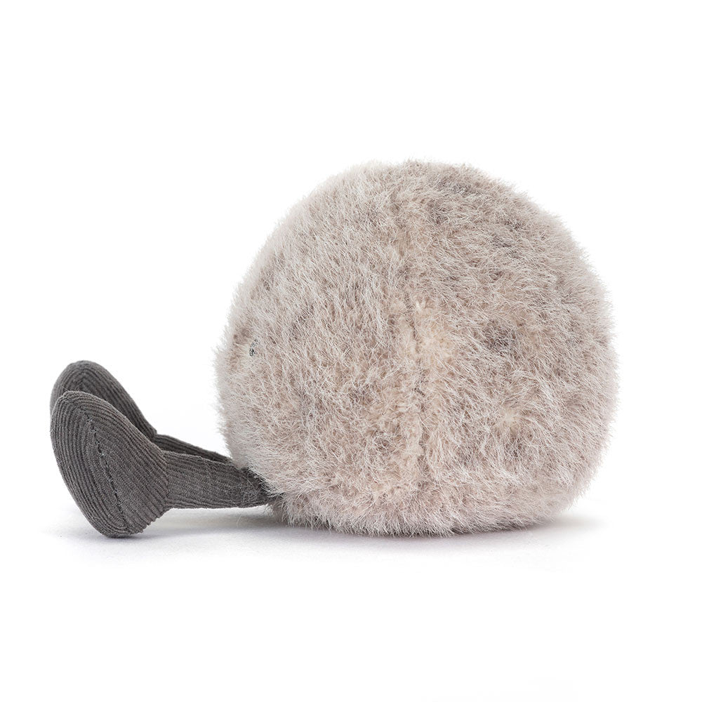 A side photo of an grey plush toy resembling a pebble with a smiling face and grey legs on a white backround.