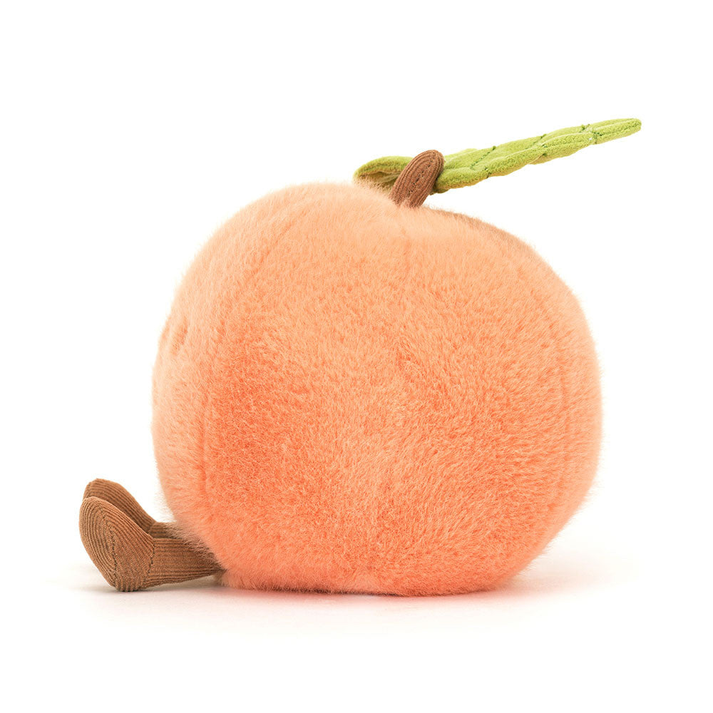 A side photo of the back of a peach coloerd plush toy shaped like a peach on a white backround. 