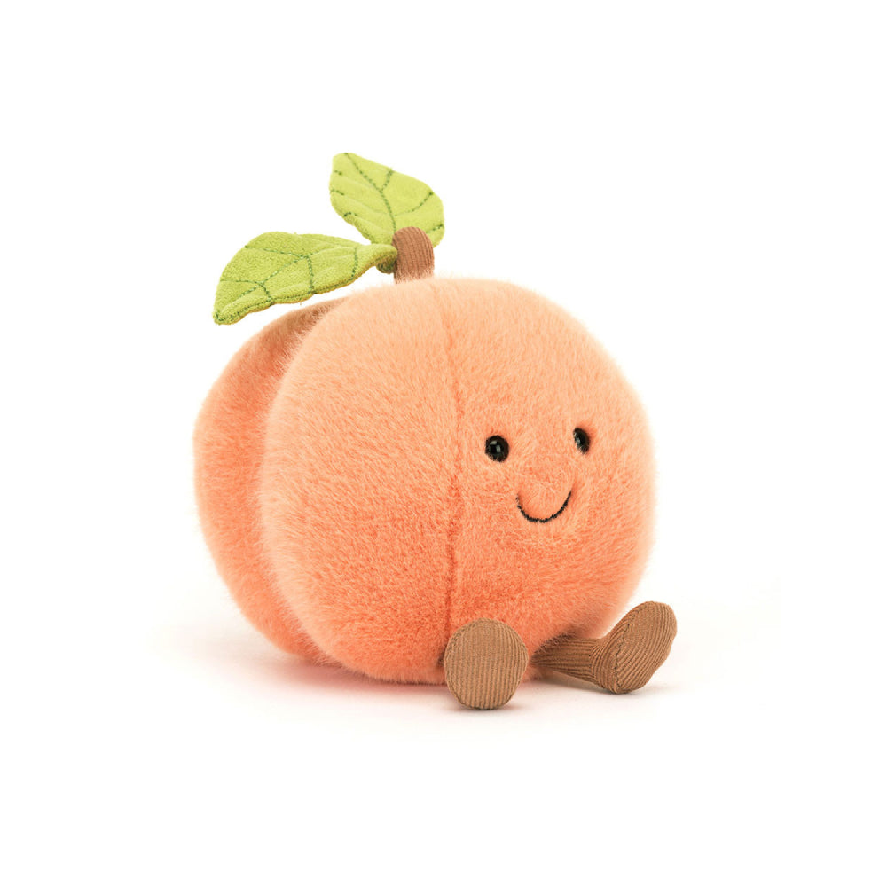 A angled photo of the back of a peach coloerd plush toy shaped like a peach on a white backround. 