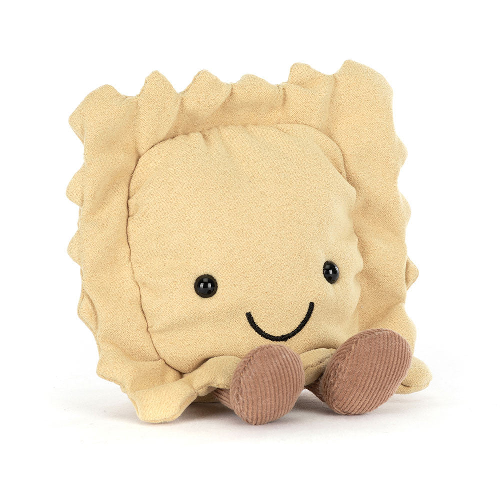 A angled side facing photo of a plush toy resembling a ravioli pasta with a smiling face, golden beige body, and brown legs on a white backround. 