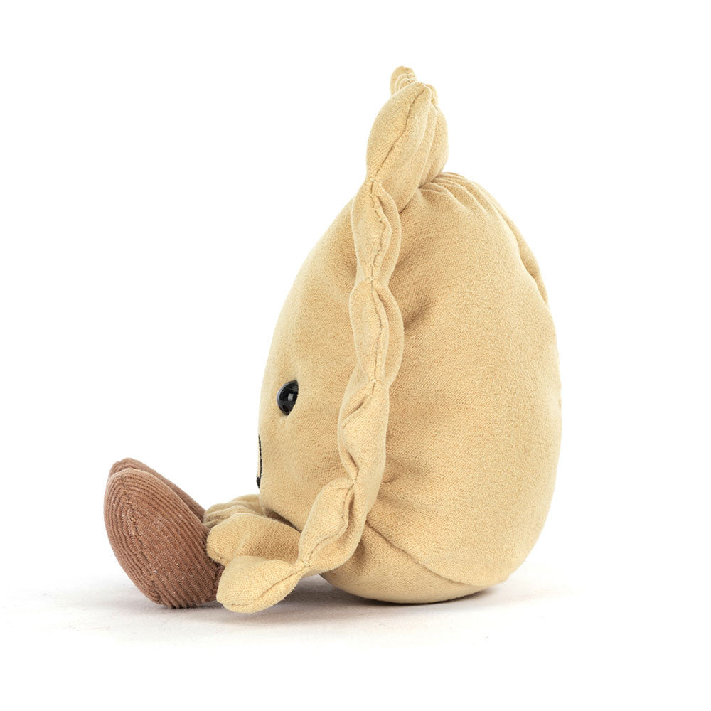 A side  photo of a plush toy resembling a ravioli pasta with a smiling face, golden beige body, and brown legs on a white backround. 