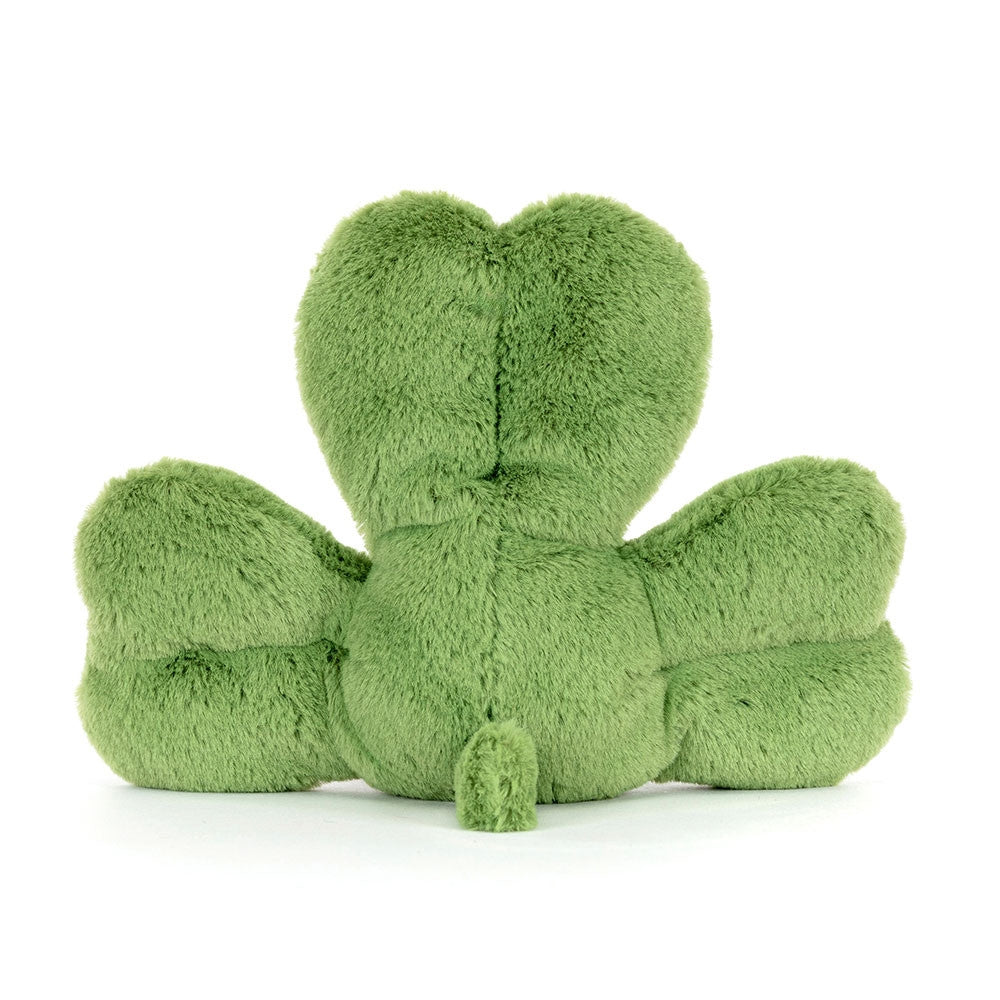 A back side facing photo of green plush shamrock toy with a happy face on a white background