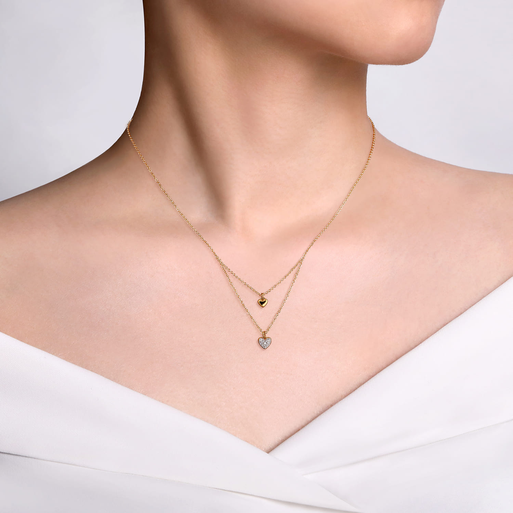 Gold necklace with heart-shaped pendant on a white background