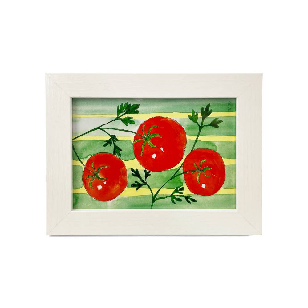 A framed watercolor painting of three red tomatoes on a green and yellow striped background, set in a white wooden frame against a white background.
