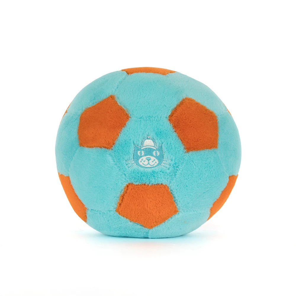 A photo of the back of a teal and orange Jellycat Amuseables Soccer Ball push toy with a smiling face and white legs on a white background.