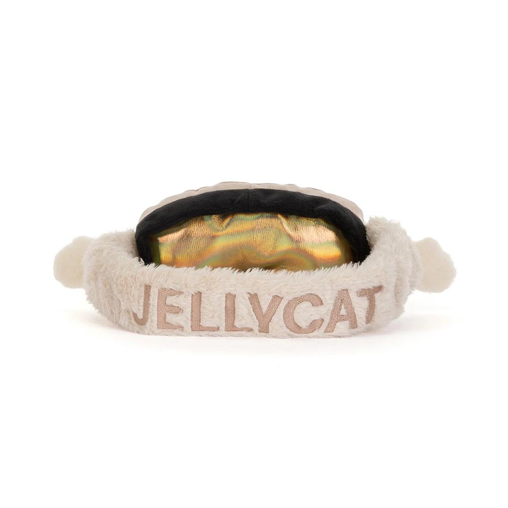A plush ski goggles with headband featuring the brand name 'JELLYCAT' embroidered in beige on the front, with a black elastic band and a shiny gold interior lining, set against a plain white background.