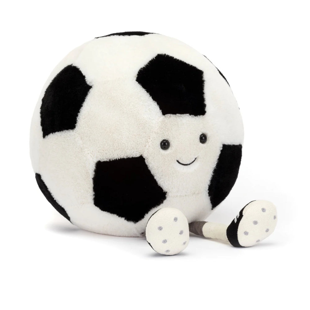 A plush toy resembling a white and black soccer ball, featuring a friendly face and legs on a white backround.