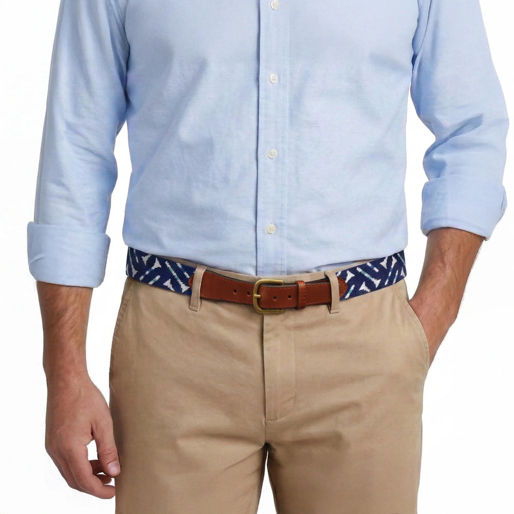 Light blue button-up shirt, beige pants, and a patterned belt worn by a person on a white background