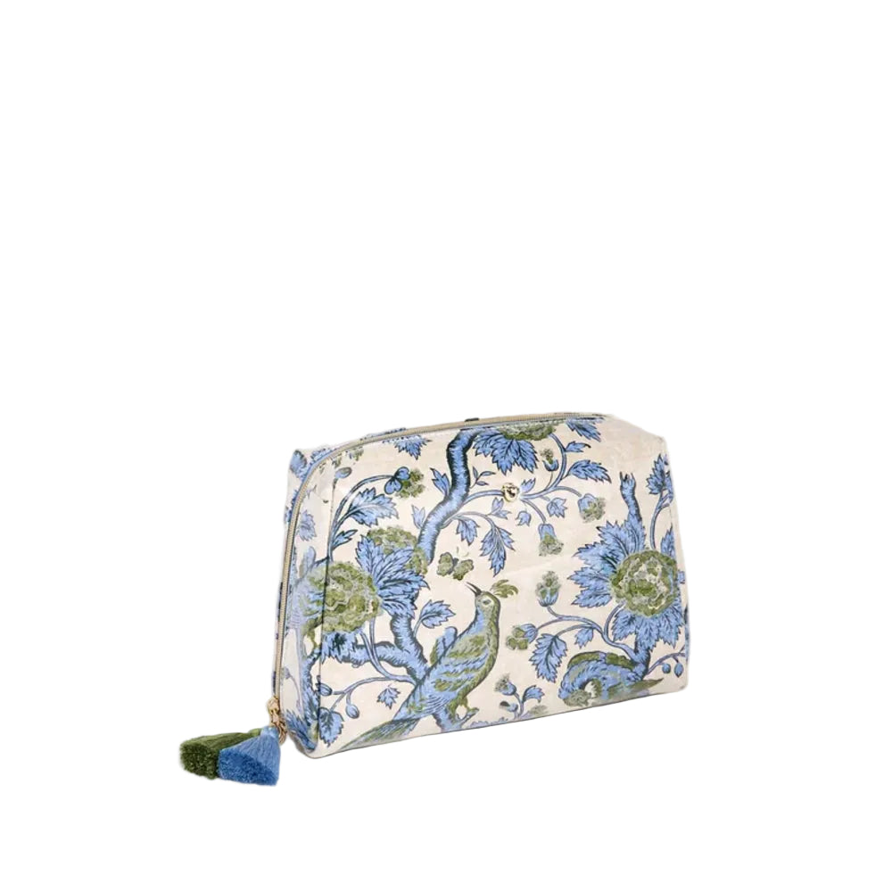 A small zippered cosmetic pouch with a blue and green floral peacock pattern on a cream background, featuring a blue and green tassel zipper pull, set against a solid cream backdrop.