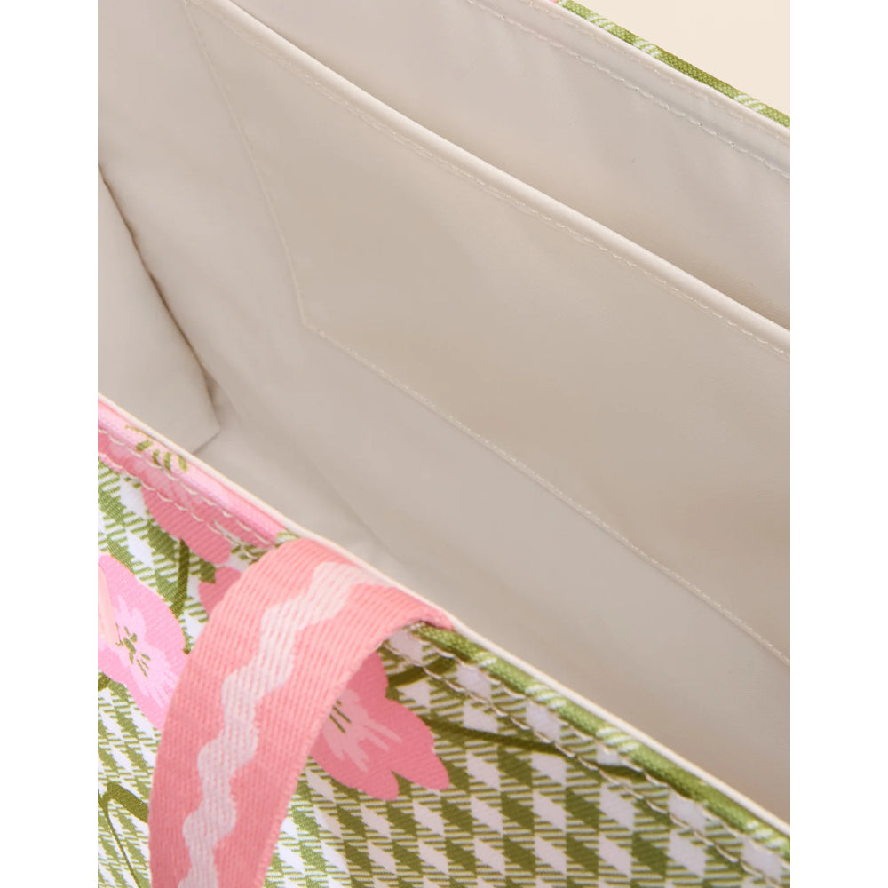Close-up of a pink floral ribbon on a green and white patterned fabric with a beige background.