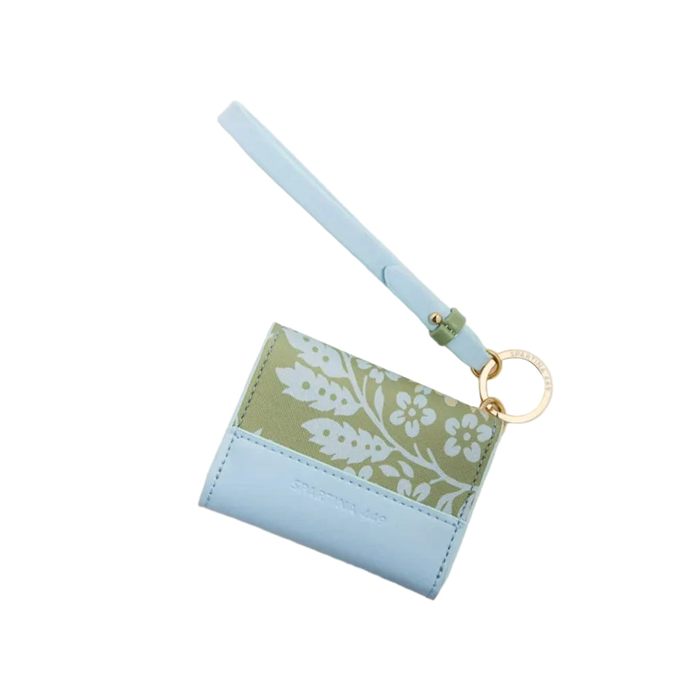 A light blue leather card holder wallet with a wristlet strap, featuring a sage green floral patterned panel and a gold-tone key ring, shown on a white background.