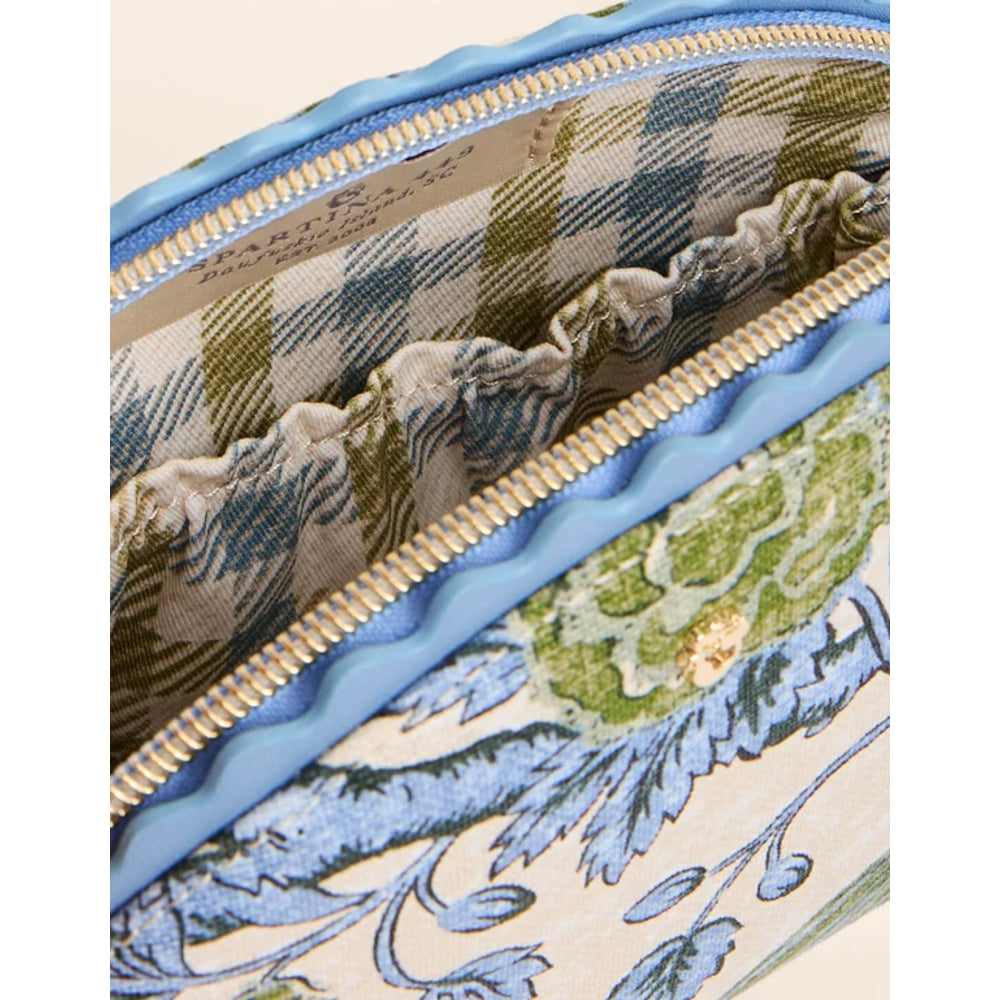 Close-up of a patterned handbag interior with a blue zipper, beige and blue plaid lining, and a floral textile exterior in blue, green, and cream.