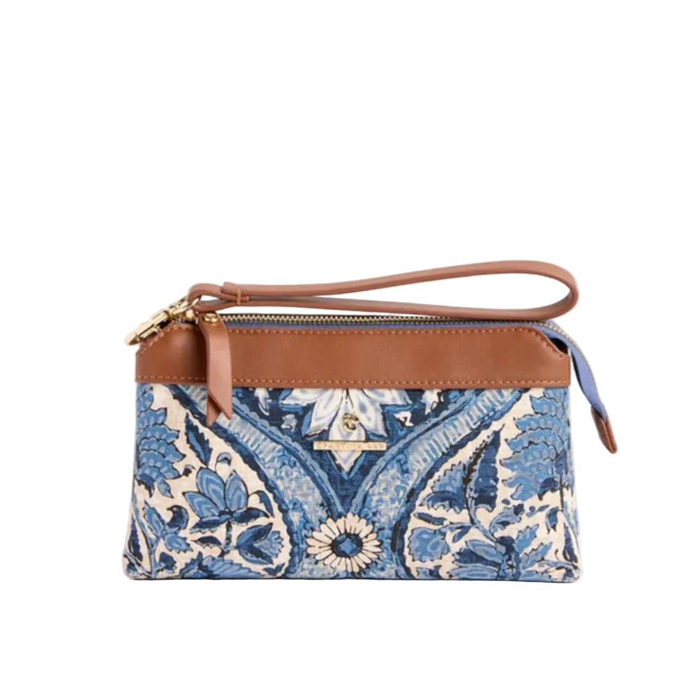 A small wristlet clutch bag with a blue and cream floral paisley pattern, brown leather trim, and a matching brown wrist strap, shown on a solid light beige background.