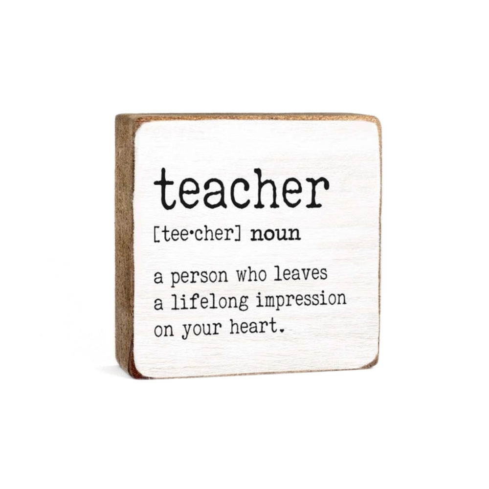 White wood  decorative square  block sign with definition of 'teacher' "a person who leaves a lifelong impression on your heart" in black text on a white background