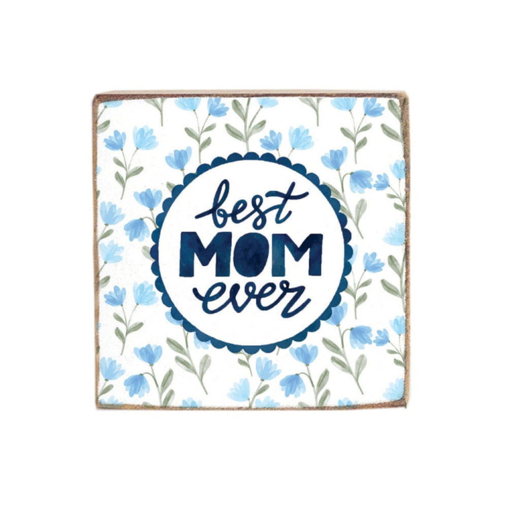 A white wooden decorative square block sign with 'best mom ever' text with a light blue floral design with navy blue text and scalloped circle egde on a white background