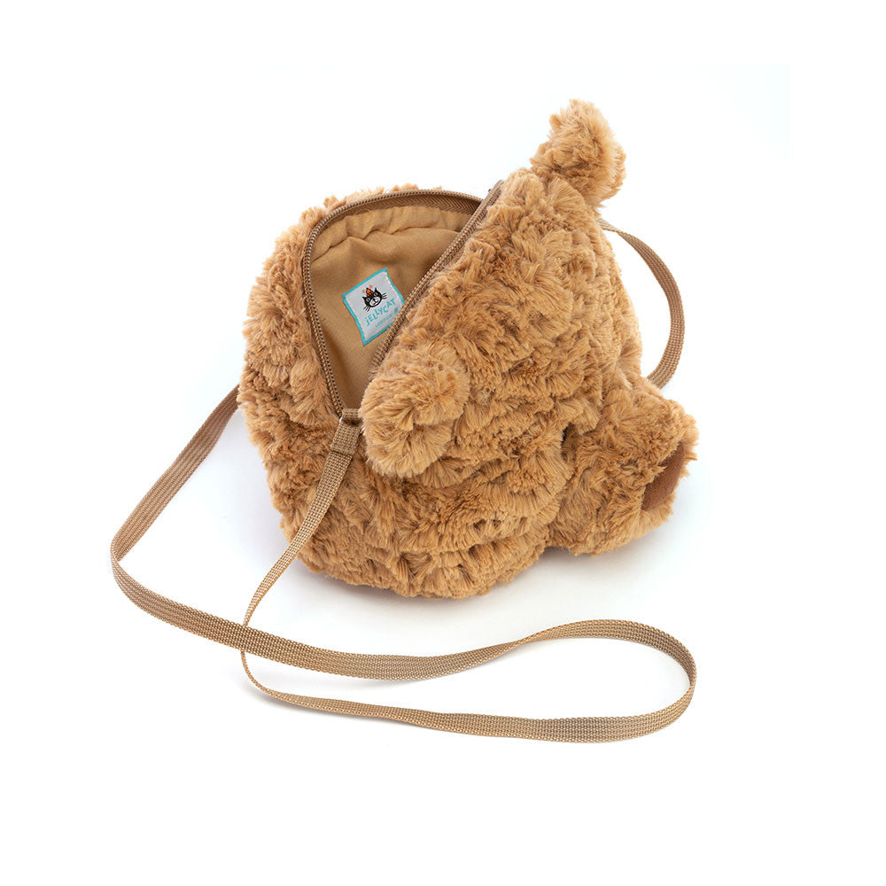A top side photo of a plush bear-shaped cross-body bag with a brown maple-syrup color, petal-fold ears, and a sturdy silver zipper. The bag has a caramel lining and a long strap.