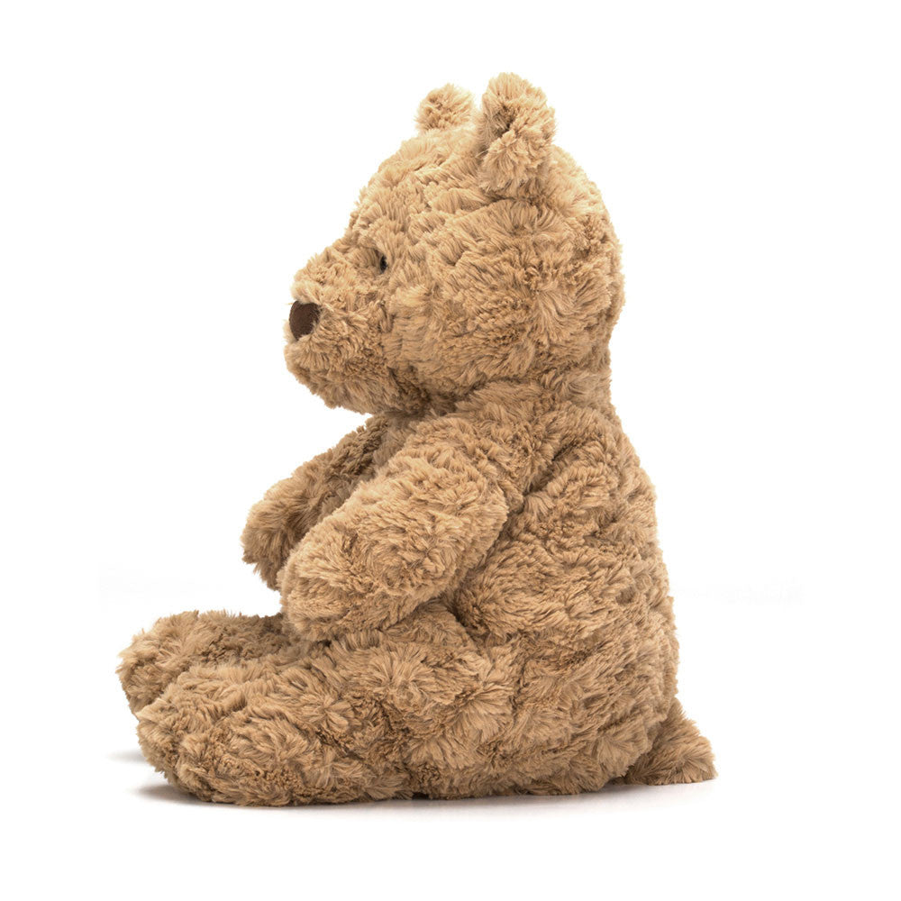 A photo of the side of huge size beige teddy bear sitting upright on a white backround.