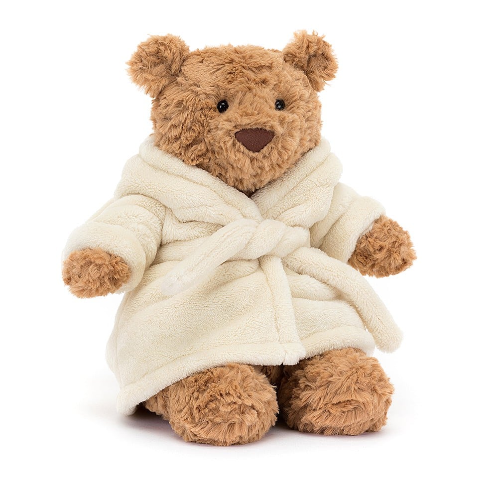 A stuffed teddy bear wearing a cream bath robe with hood off the has bunny ears on a white background.