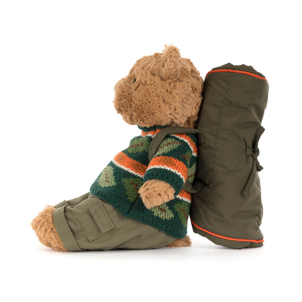 A side photo of a teddy bear wearing a sweater and carrying a backpack on a white background.