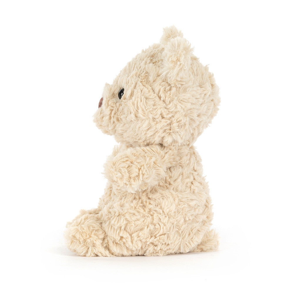 A side photo of an fluffy beige plush toy on a white background.